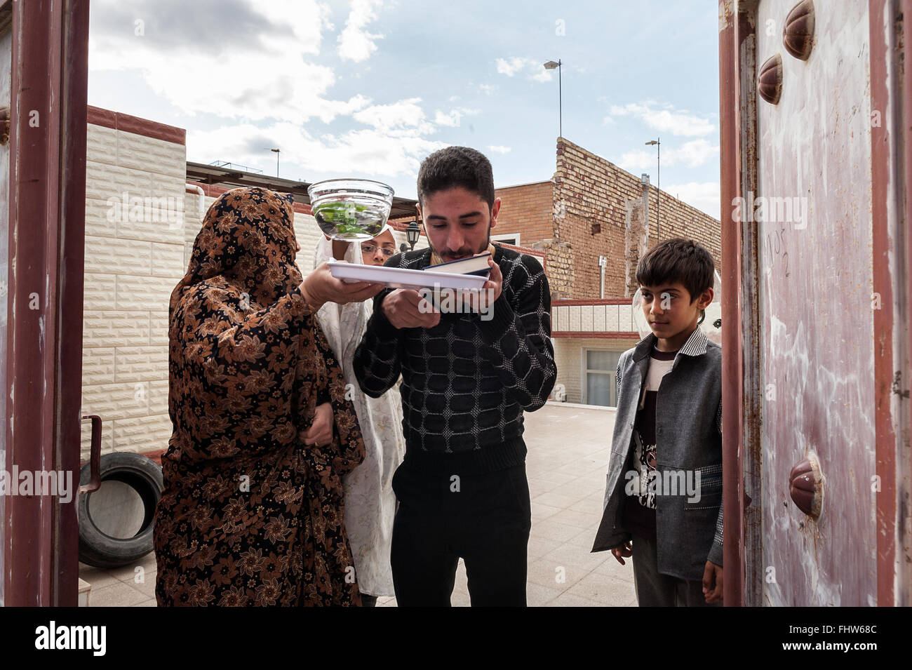 Hossein is about to leave for the pilgrimage to Karbala (Iraq). Before leaving his family, he kisses the Koran three times and the rest of the family pulls water to purify him from malefic. (Photo by Claudia Borgia / Pacific Press) Stock Photo