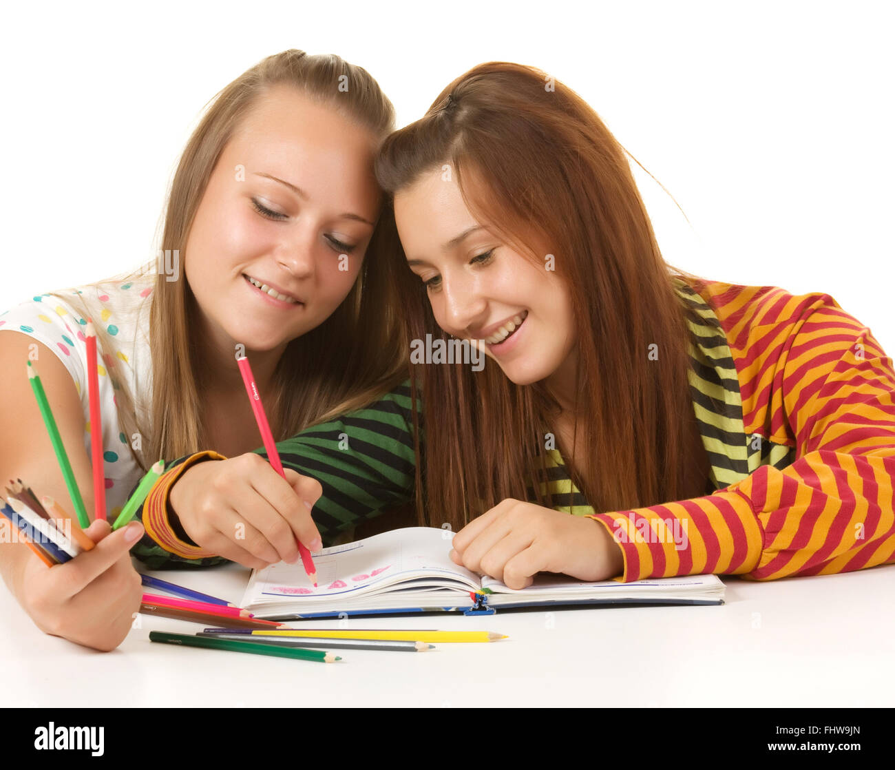 Two teenage girls smiling and reading book Stock Photo
