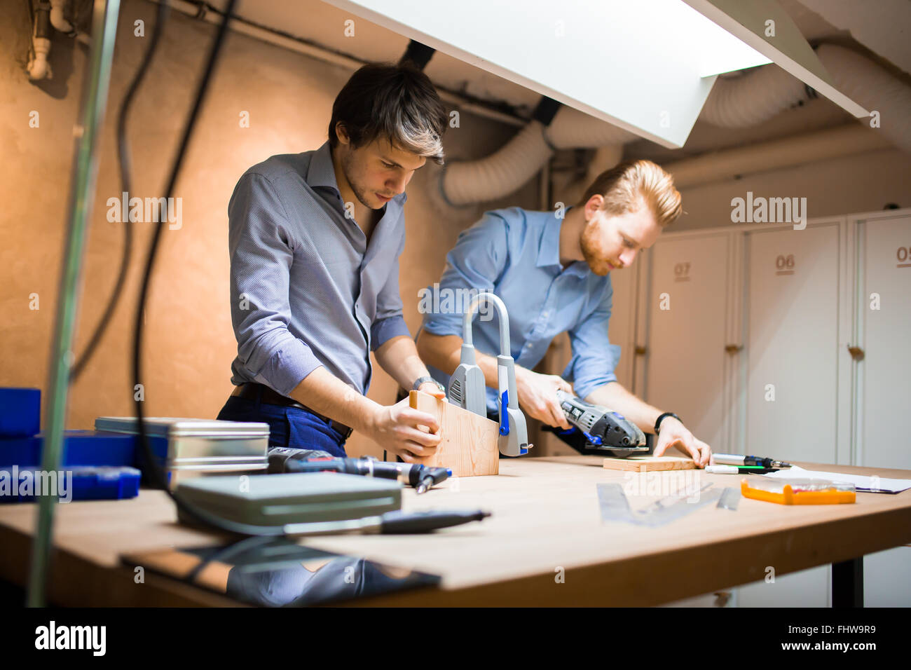 Two creative designers working in workshop with precision tools manufacturing a new product Stock Photo
