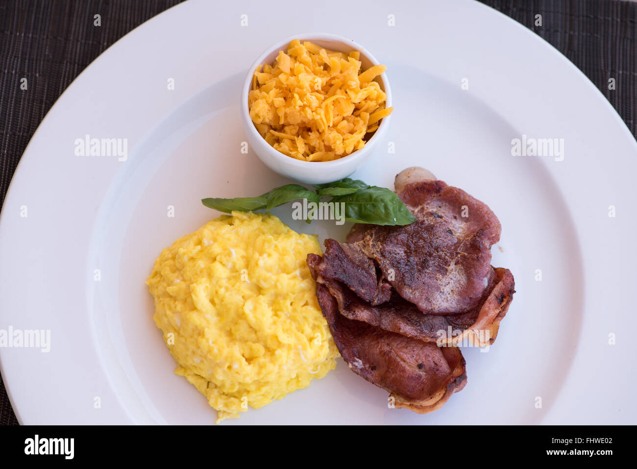 Overhead view of scrambled eggs, bacon and grated cheese breakfast Stock Photo