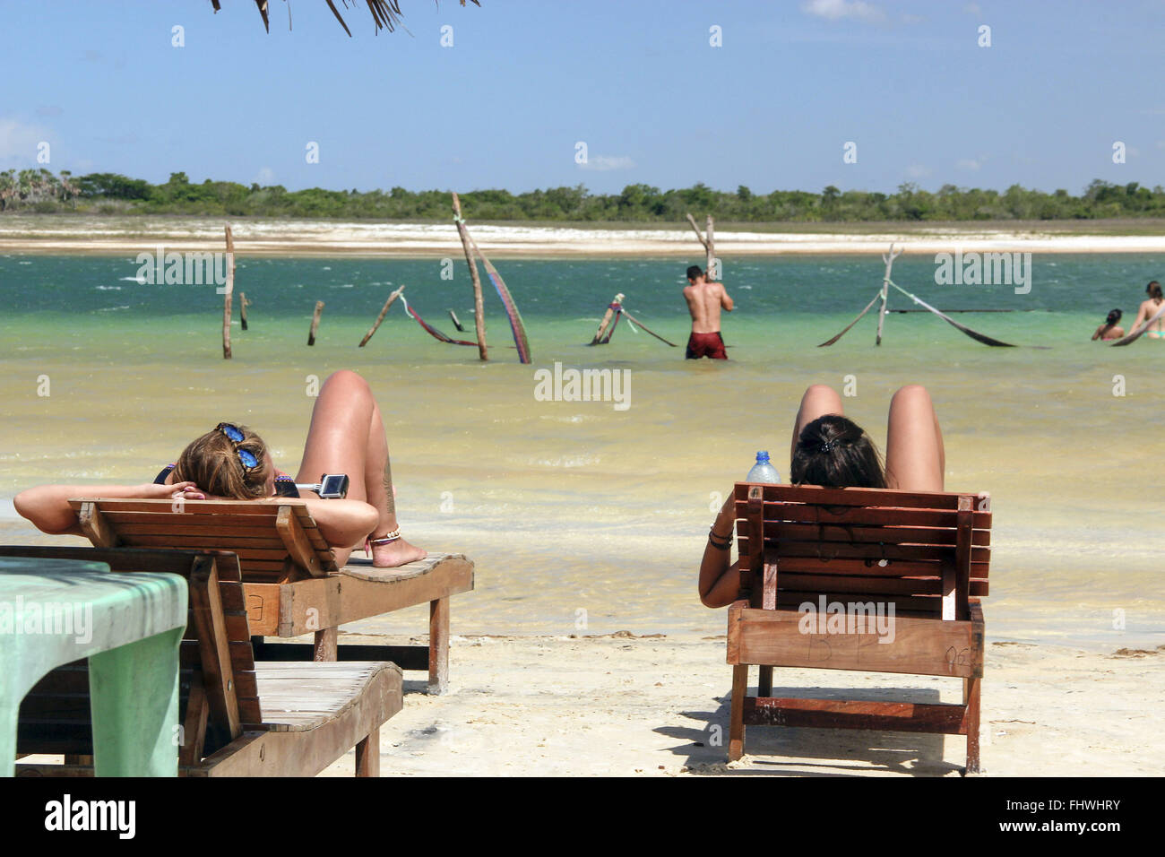 Turistas tomando sol e redes de descanso na Lagoa Paraíso ao fundo Stock Photo
