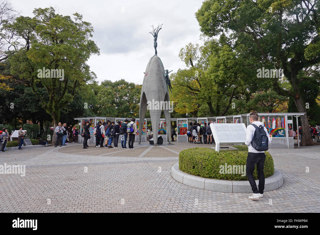Students visit the Children's Monument, Hiroshima Memorial Peace Park, Japan Behind are stalls where the paper cranes are kept Stock Photo
