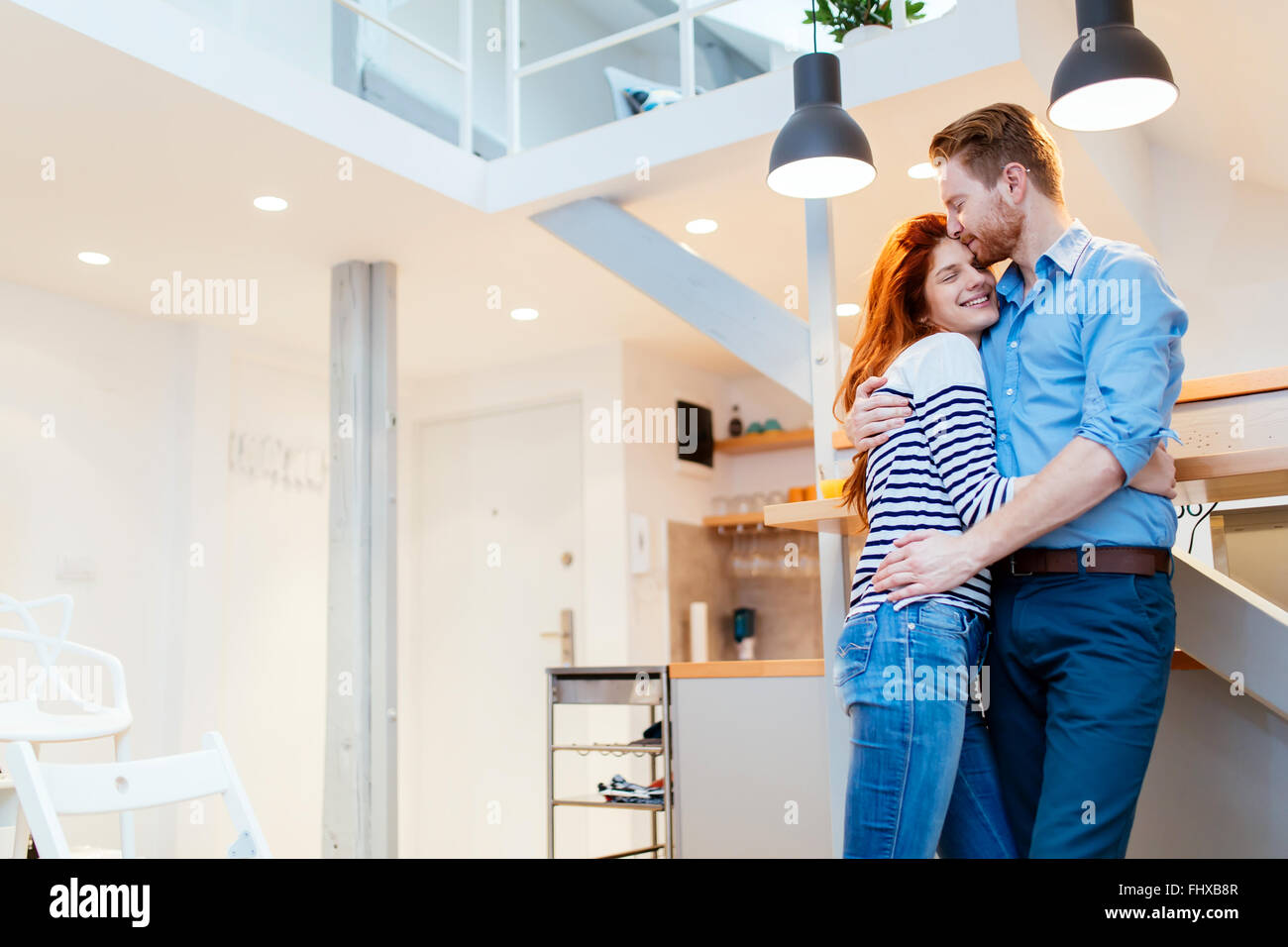 Couple enjoying their new luxurious home and hugging in living room Stock Photo