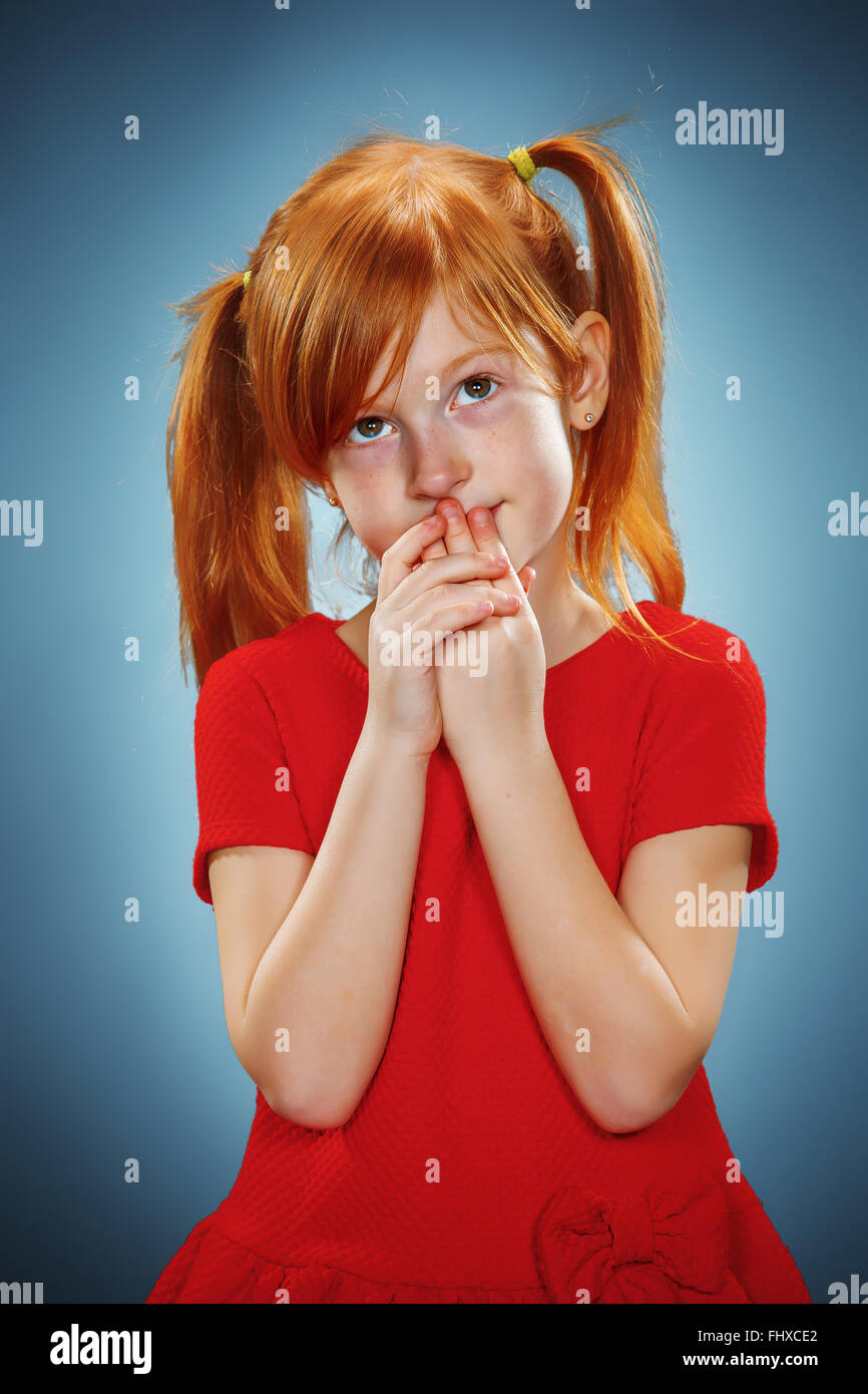 The beautiful portrait of a thoughtful little girl with red hair in red ...