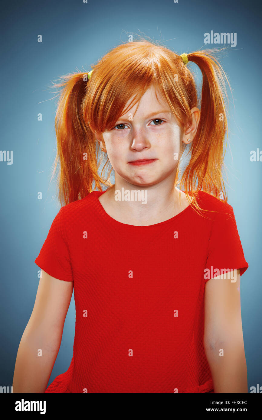 The beautiful portrait of a thoughtful little girl with red hair in red ...
