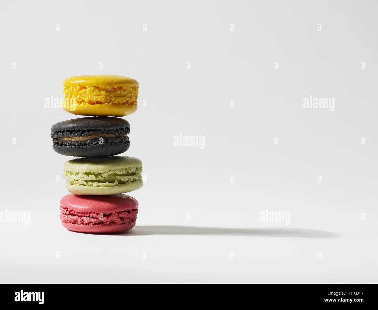 Stack of four yellow, brown, green and pink macaroons Stock Photo
