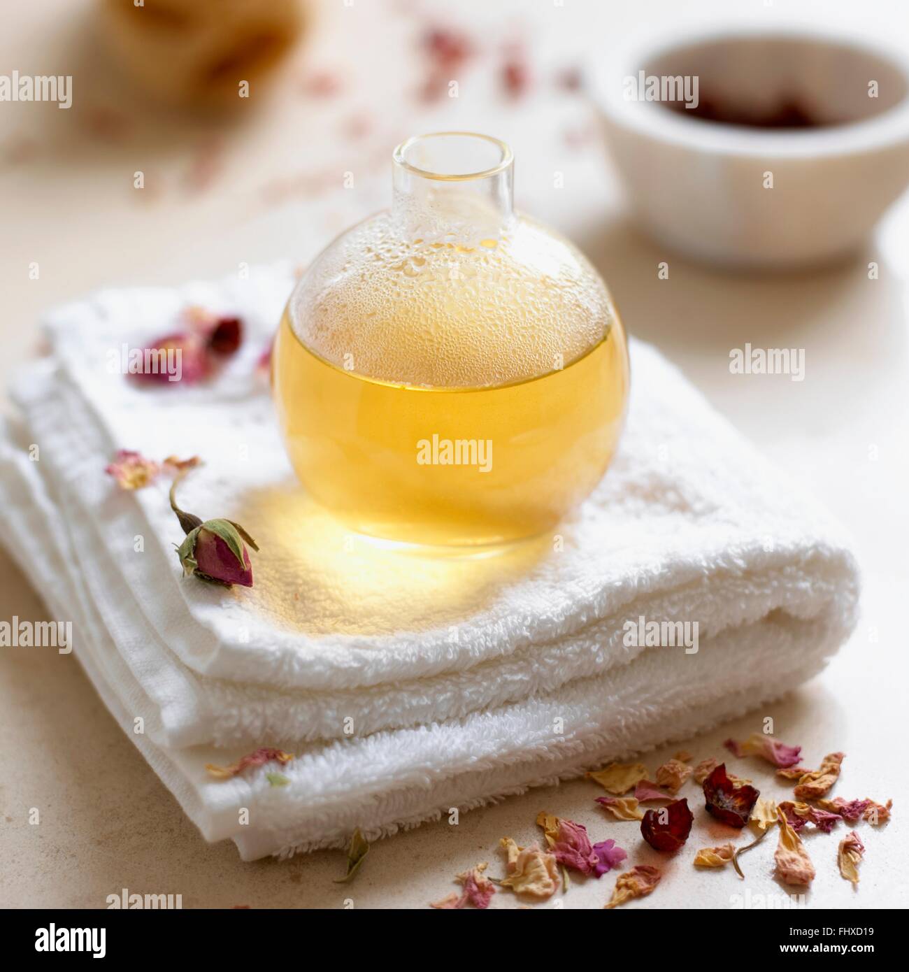 Bottle of rose and marigold bath oil, on folded towel Stock Photo