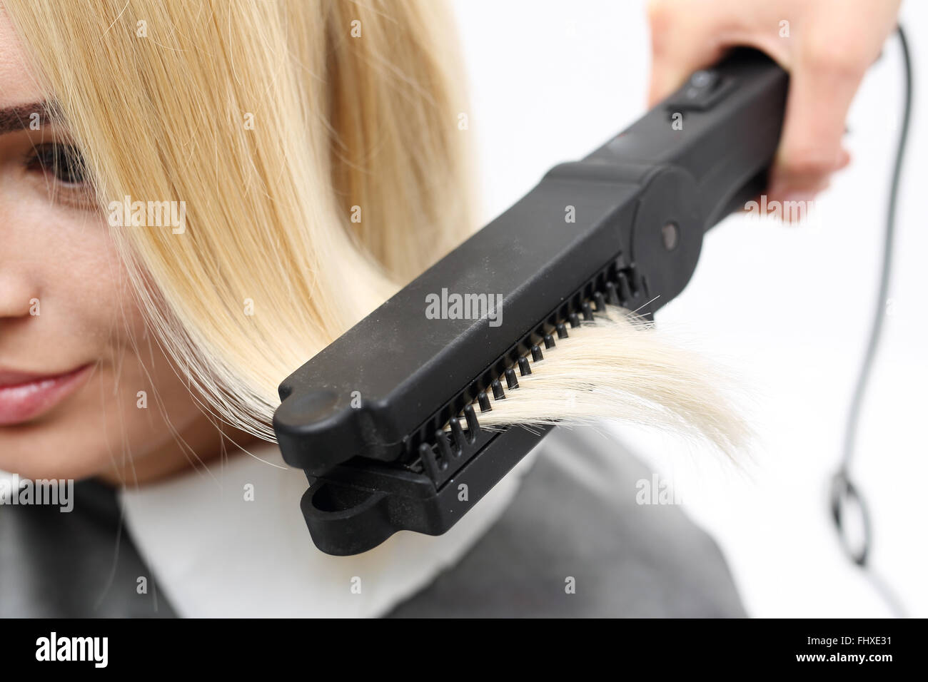 Iron barbershops, hair straightening.. Keratin hair straightening.. Hairdresser hairstyle models using the straightener . Stock Photo