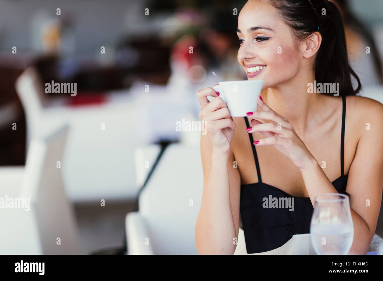 Beautiful woman drinking tea in restaurant while waiting for her meal