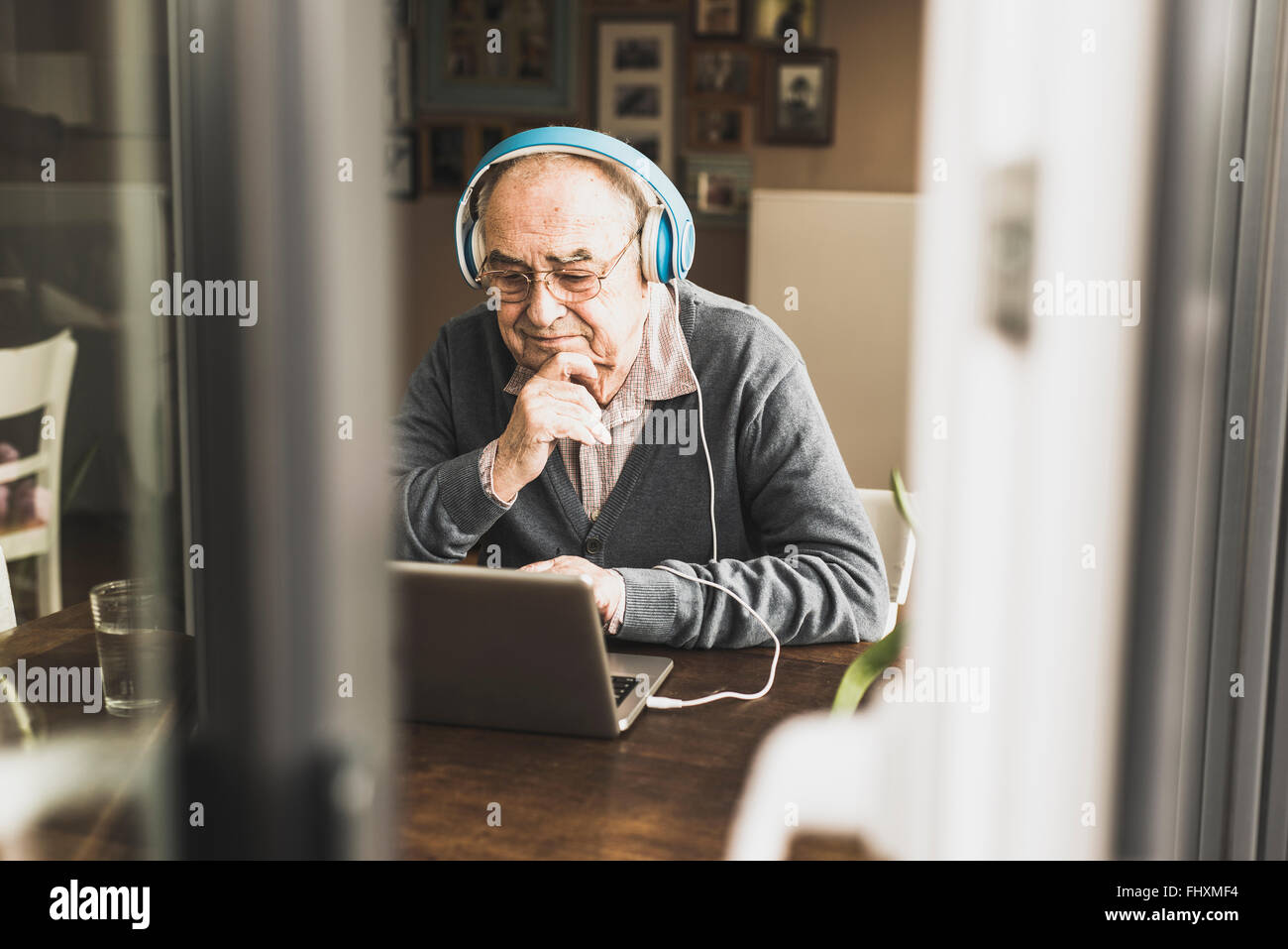 Senior man using laptop and headphones at home Stock Photo