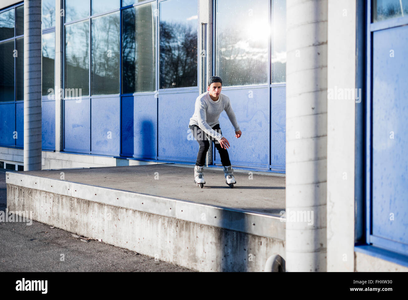 Young man inline skating along a building Stock Photo