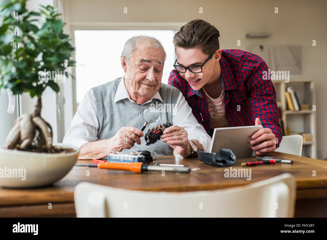 Portrait of senior man and grandson with toy train and mini tablet at home Stock Photo