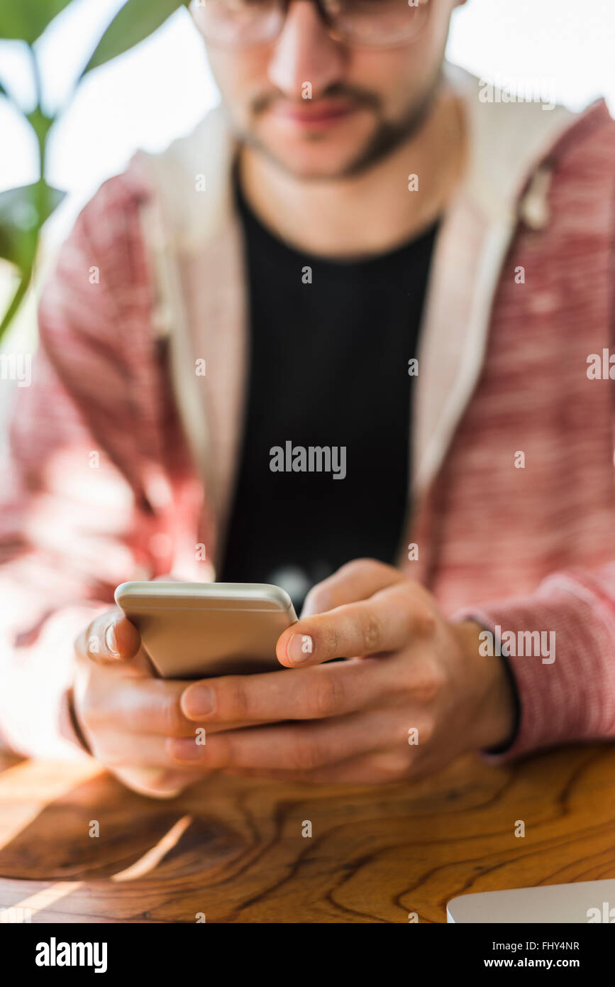 Close-up of man with cell phone at desk Stock Photo