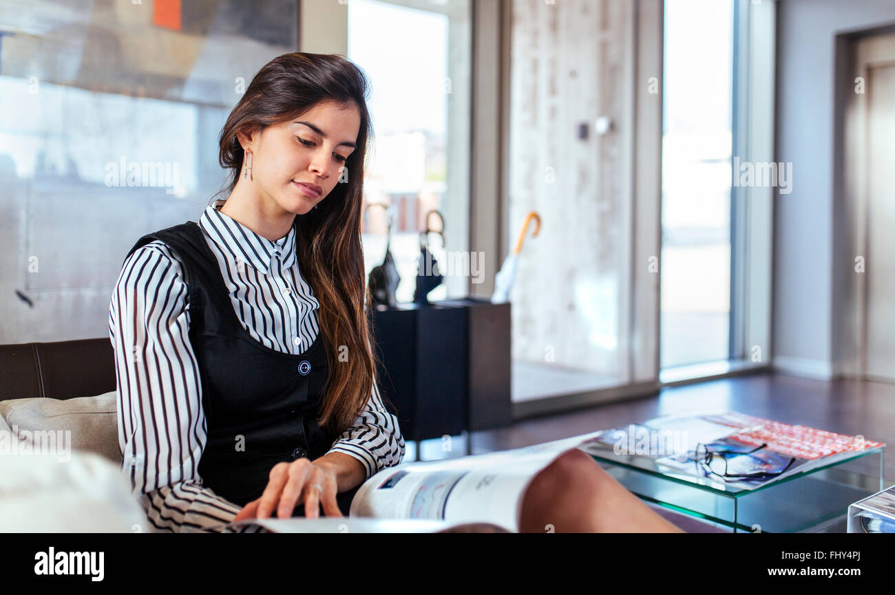 Young Woman Reading Magazine At Waiting Area Of An Office Stock