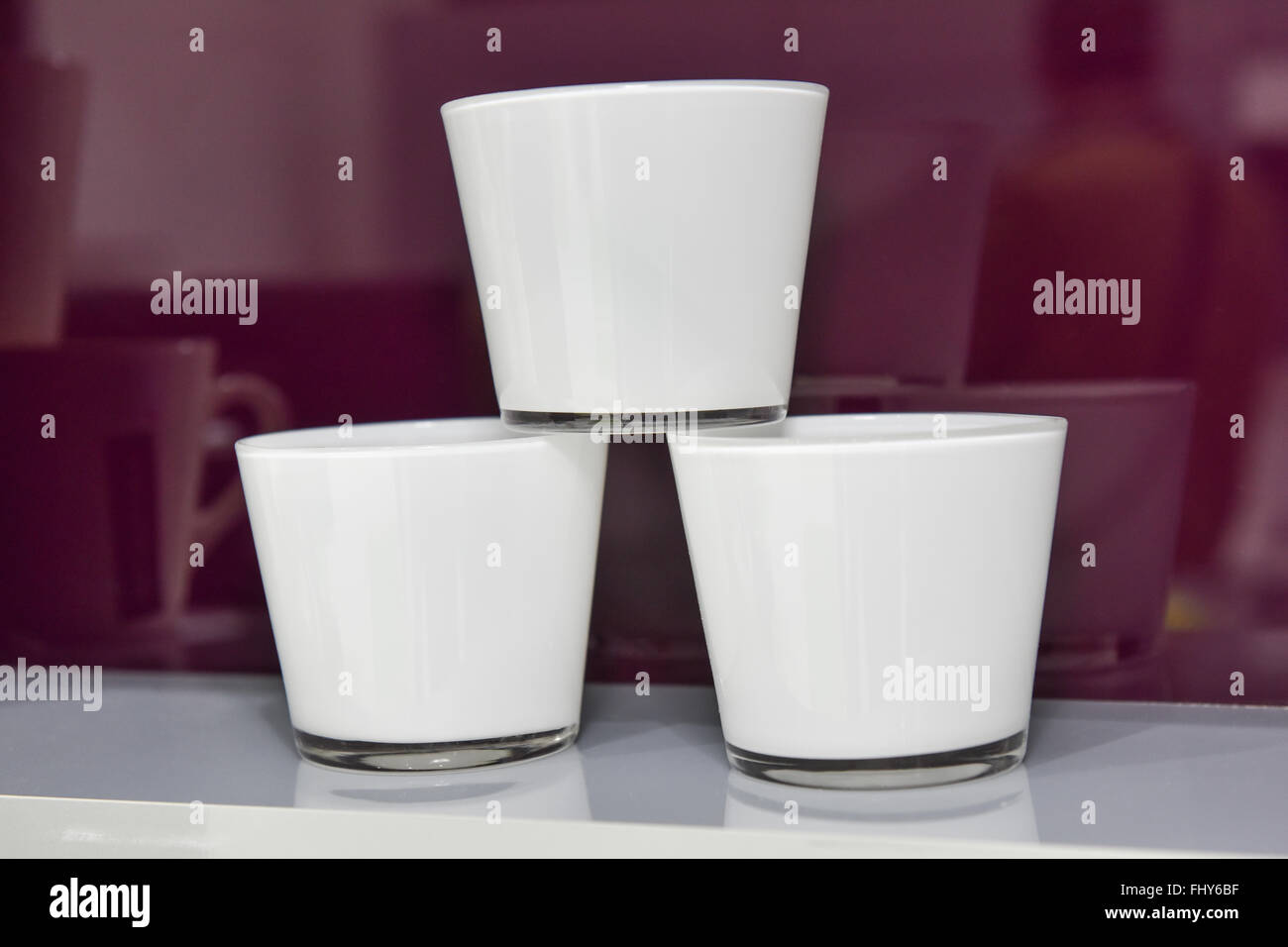 Three small white cups stacked on a kitchen shelf Stock Photo