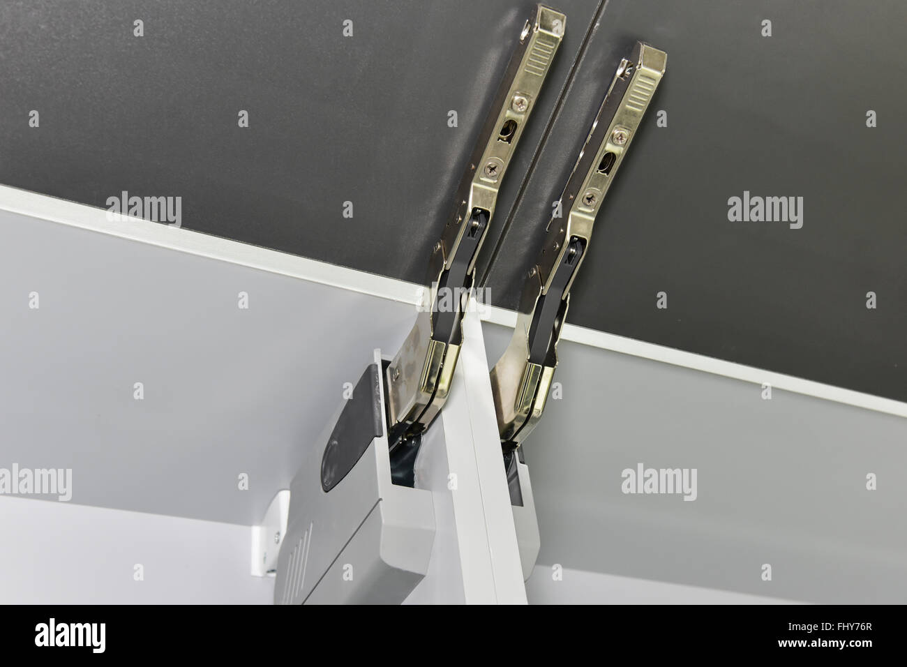 Closeup detail of an actuator hinge on door of a kitchen cupboard Stock