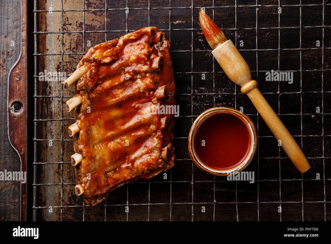 BBQ grilled smoked pork ribs and sauce brush on dark metal baking sheet background Stock Photo