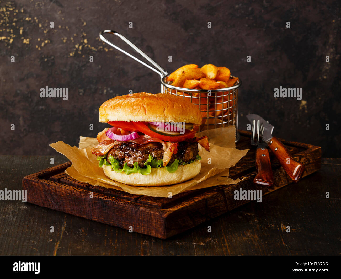 Burger with meat and potato wedges on dark background Stock Photo