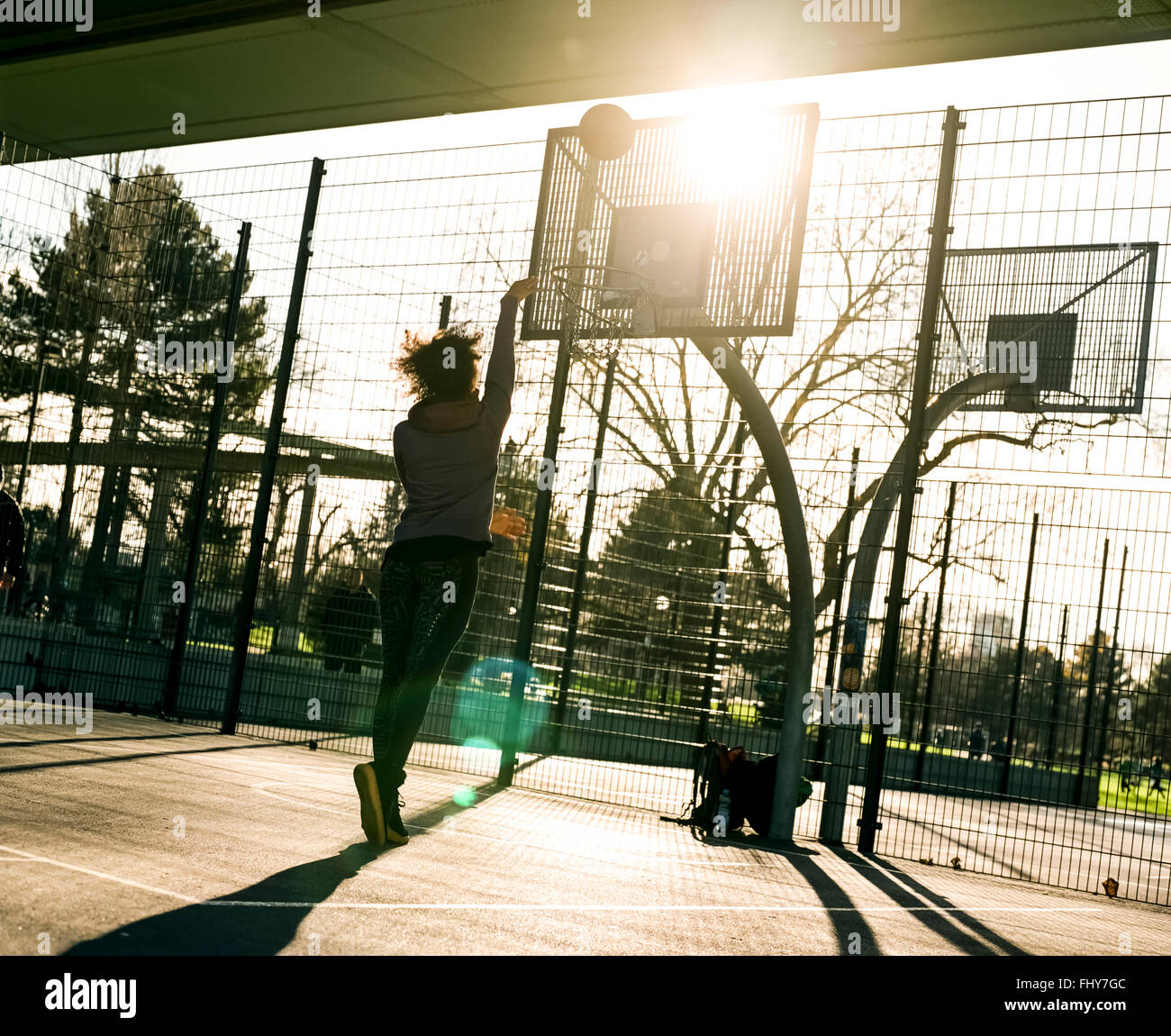 Back view of young woman throwing basketball on a playing field Stock Photo