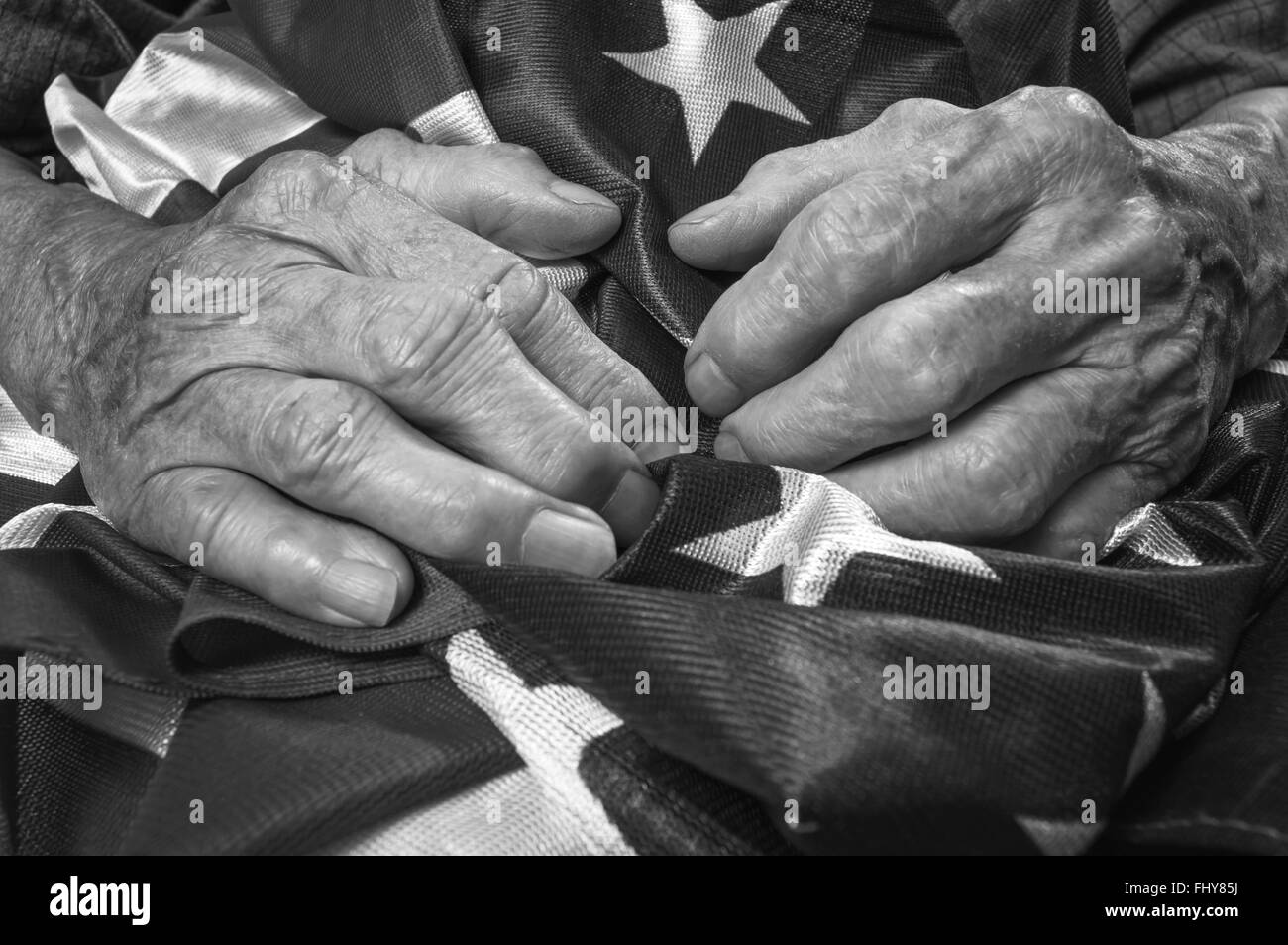 Old woman's hands holding an American flag. Black and white image. Selective focus. Stock Photo