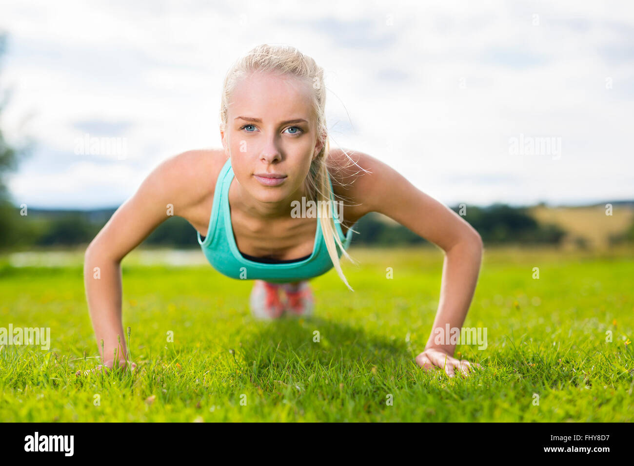 Blonde woman doing push-ups in the park Stock Photo