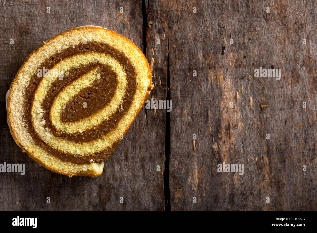 Chocolate roll cake with caramel and vanilla sauce over wooden background with copy space Stock Photo