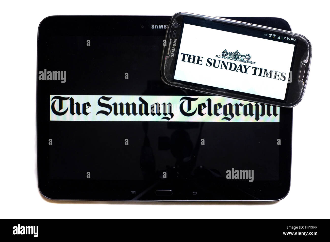 The logos of The Sunday Telegraph and The Sunday Times newspapers displayed on the screens of a tablet and a smartphone. Stock Photo