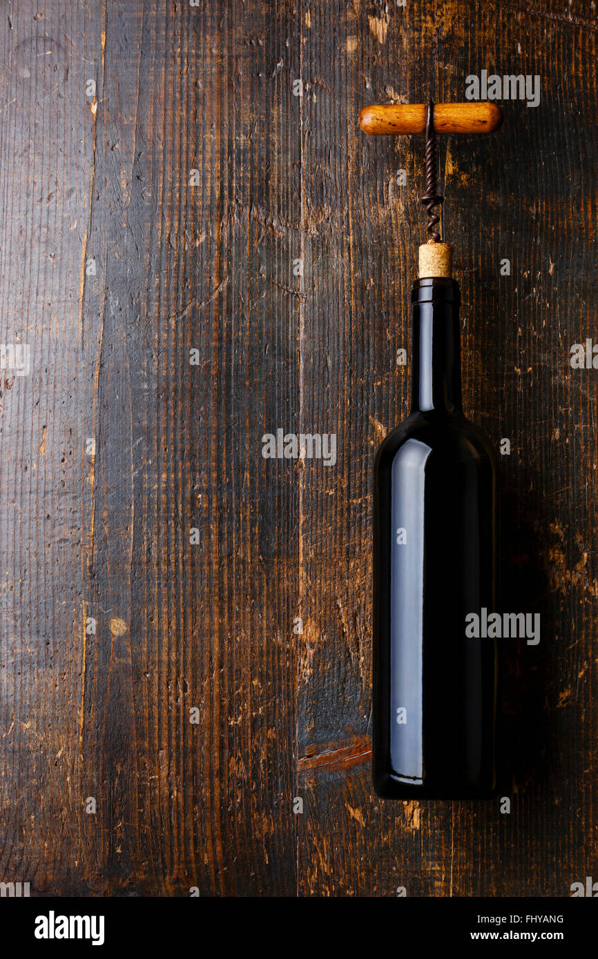 Wine bottle and corkscrew on dark wooden background Stock Photo