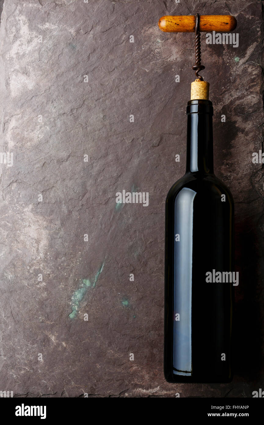 Wine bottle and corkscrew on stone slate background Stock Photo
