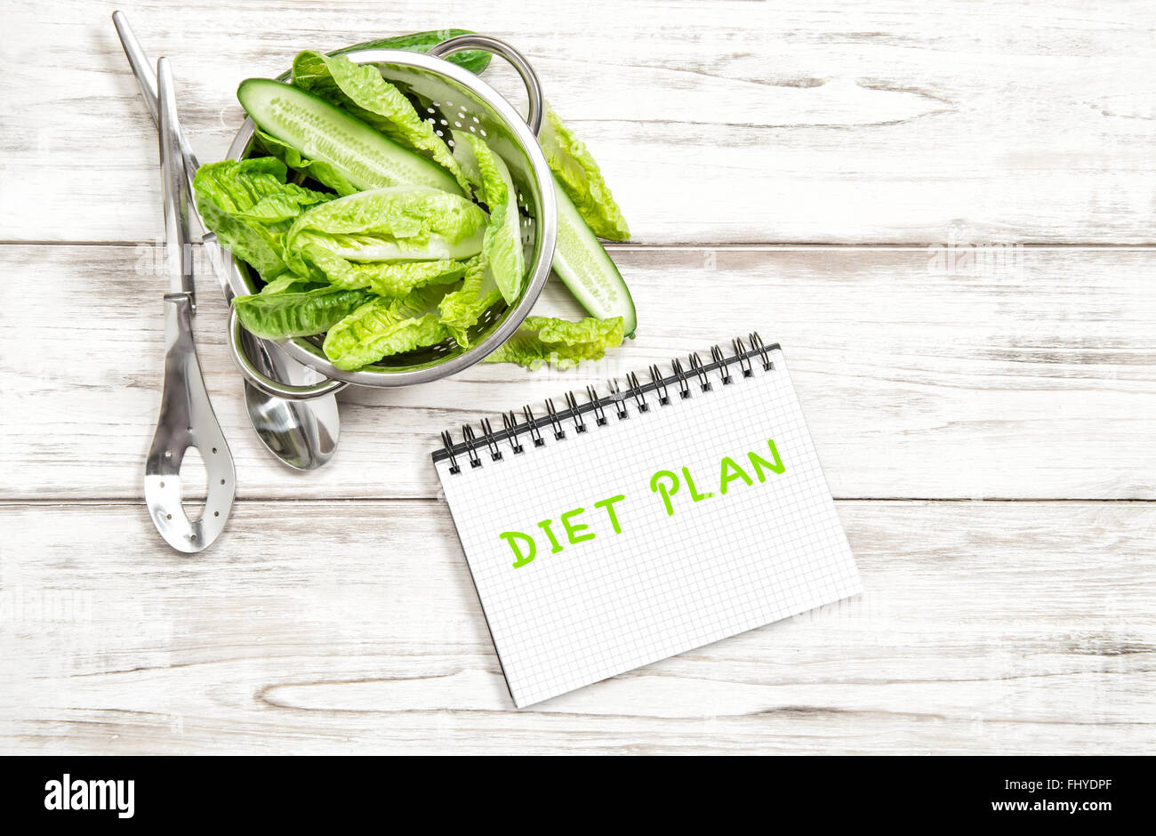 Green salad leaves and vegetables with diet plan journal on white wood kitchen table. Healthy food concept Stock Photo