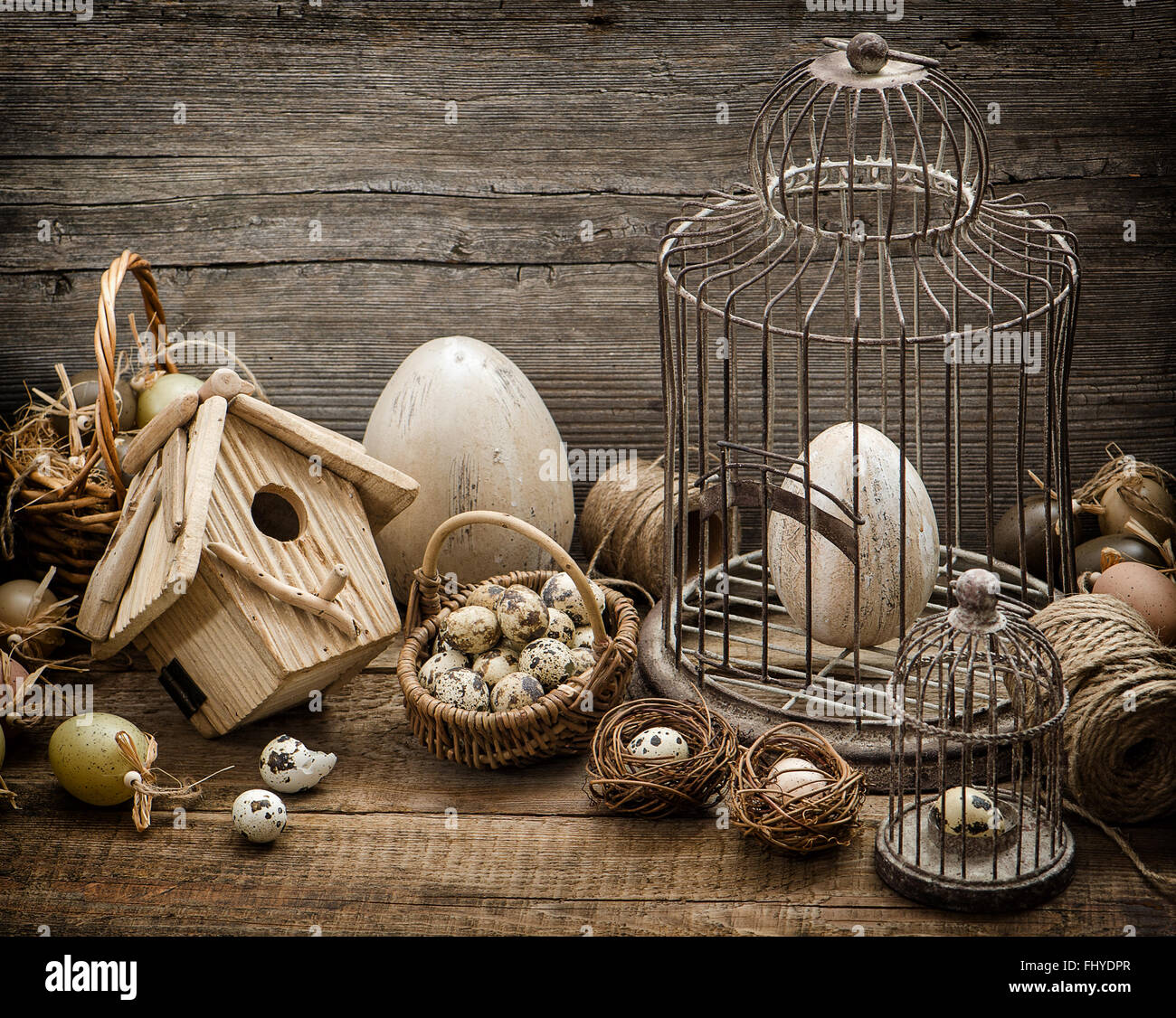 Easter decoration with eggs, birdhouse and birdcage. Nostalgic still life home interior. Vintage style toned picture Stock Photo