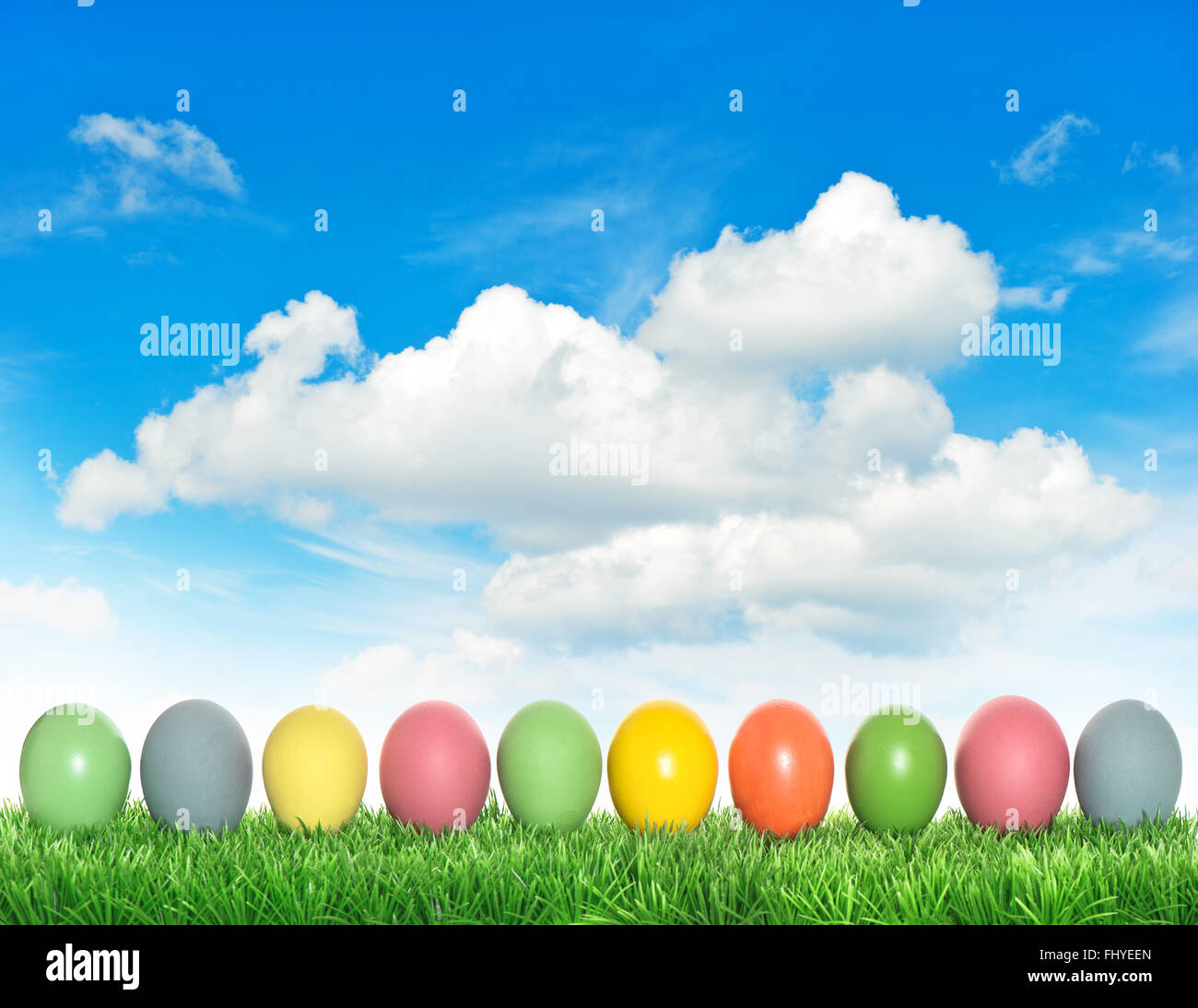 Easter eggs in green grass over cloudy blue sky background Stock Photo ...