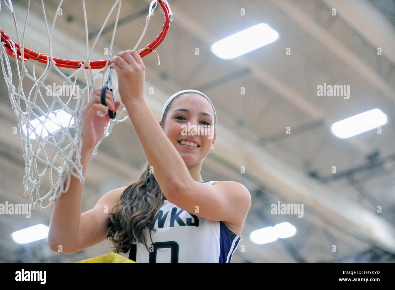 After winning a high school regional tournament title game, team members exercise tradition by individually cutting down a net. Stock Photo