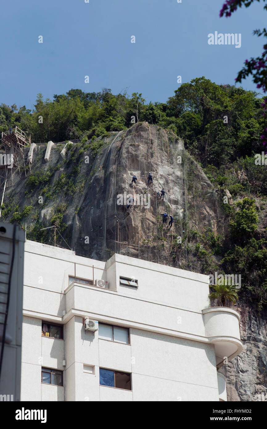 Brazilian workers drilling rock for rock contention behind apartment ...