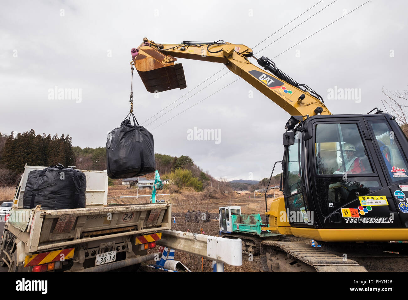 Bags containing irradiated debris are stacked on trucks in an area that was affected by the 2011 tsunami and nuclear disaster. Stock Photo
