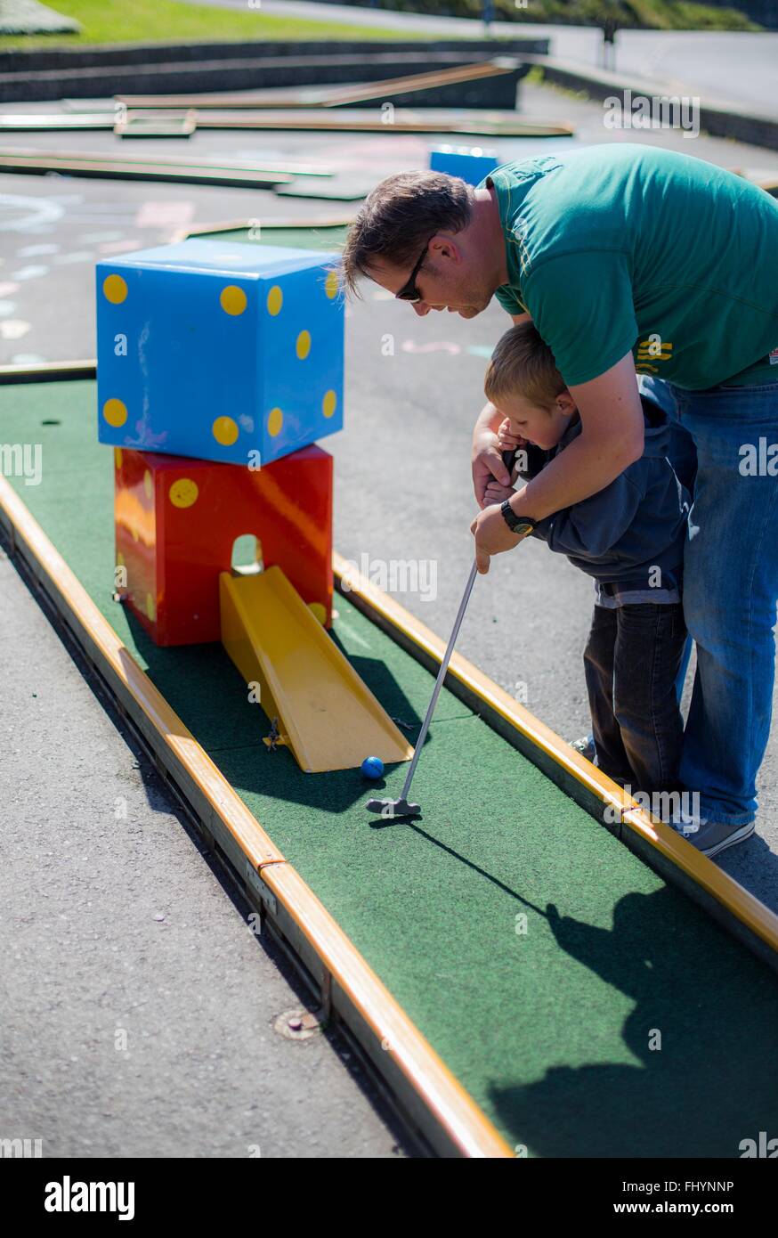 MODEL RELEASED. Father helping son to play mini golf. Stock Photo