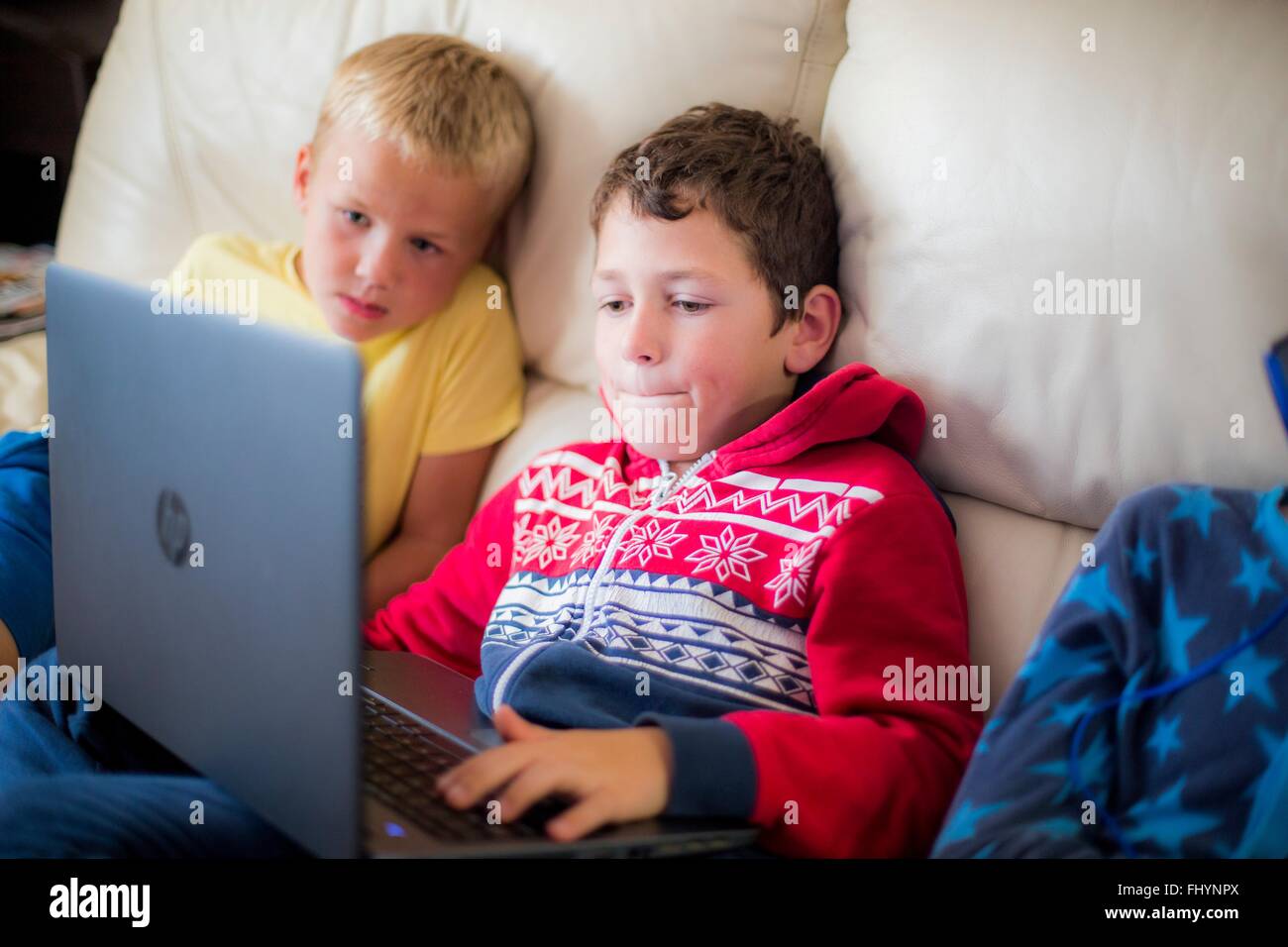 MODEL RELEASED. Two boys using a laptop sitting on the sofa Stock Photo ...