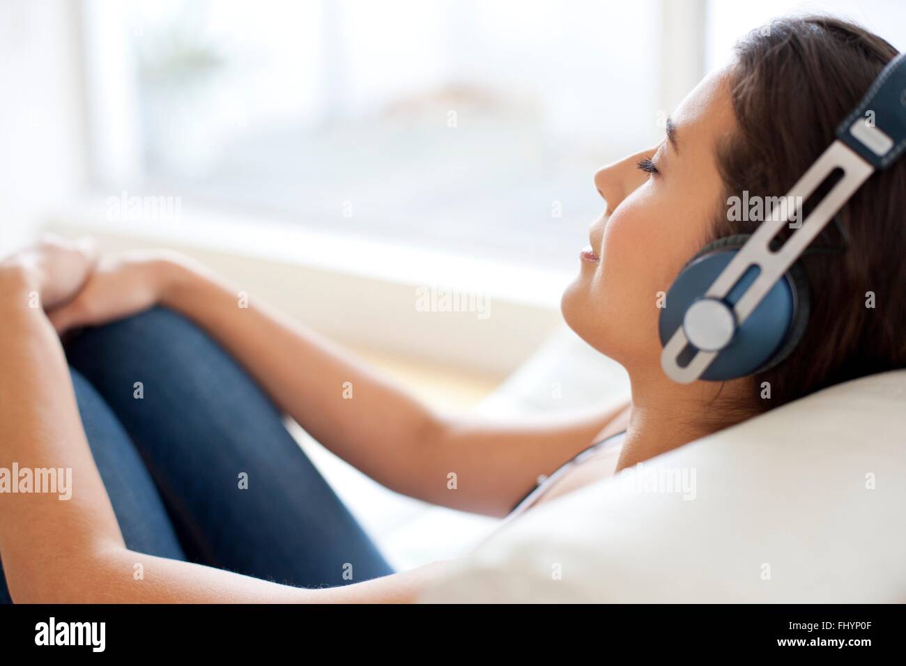 MODEL RELEASED. Woman lying down wearing headphones, relaxing Stock