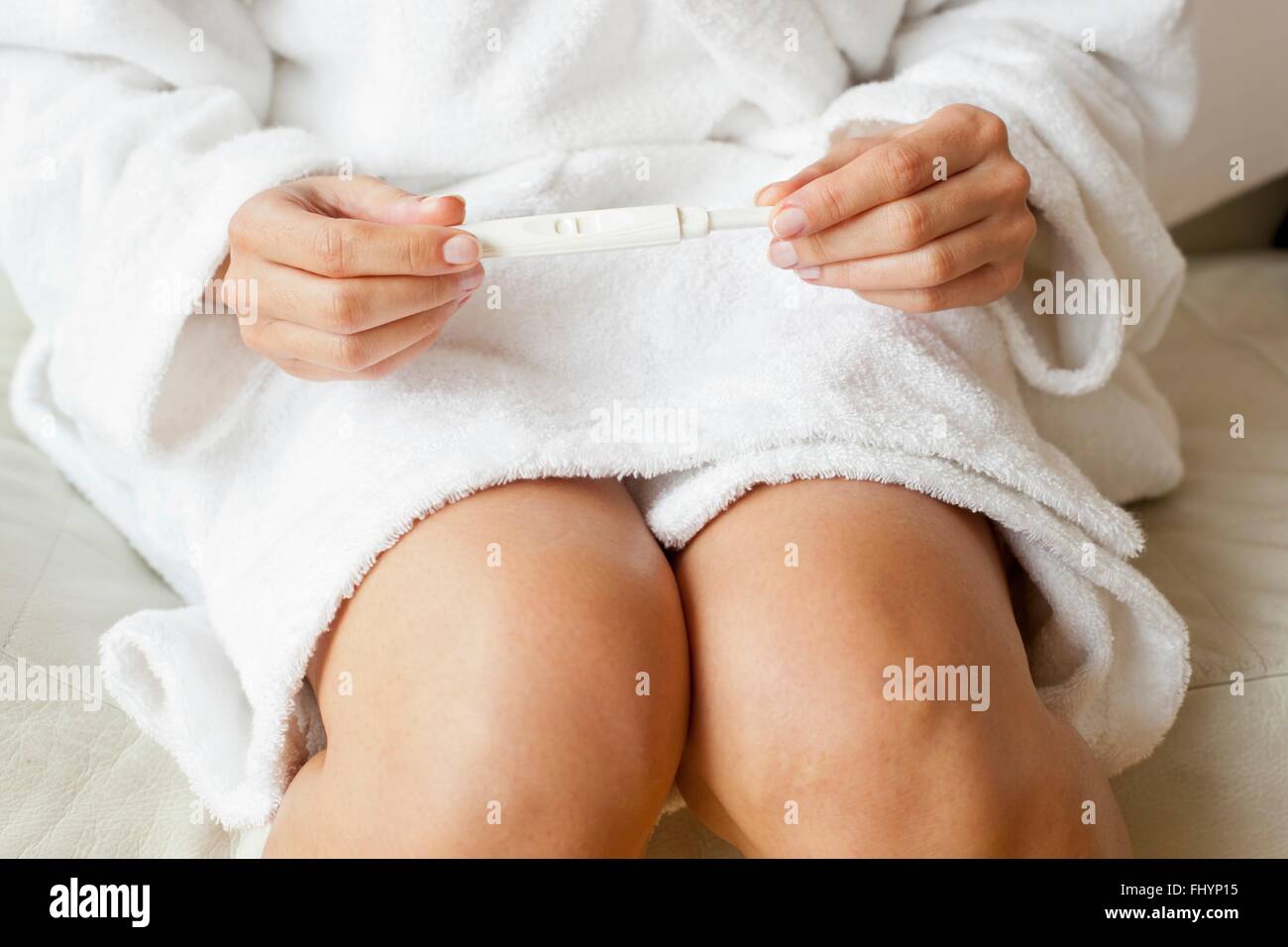 MODEL RELEASED. Woman wearing dressing gown taking a pregnancy test. Stock Photo