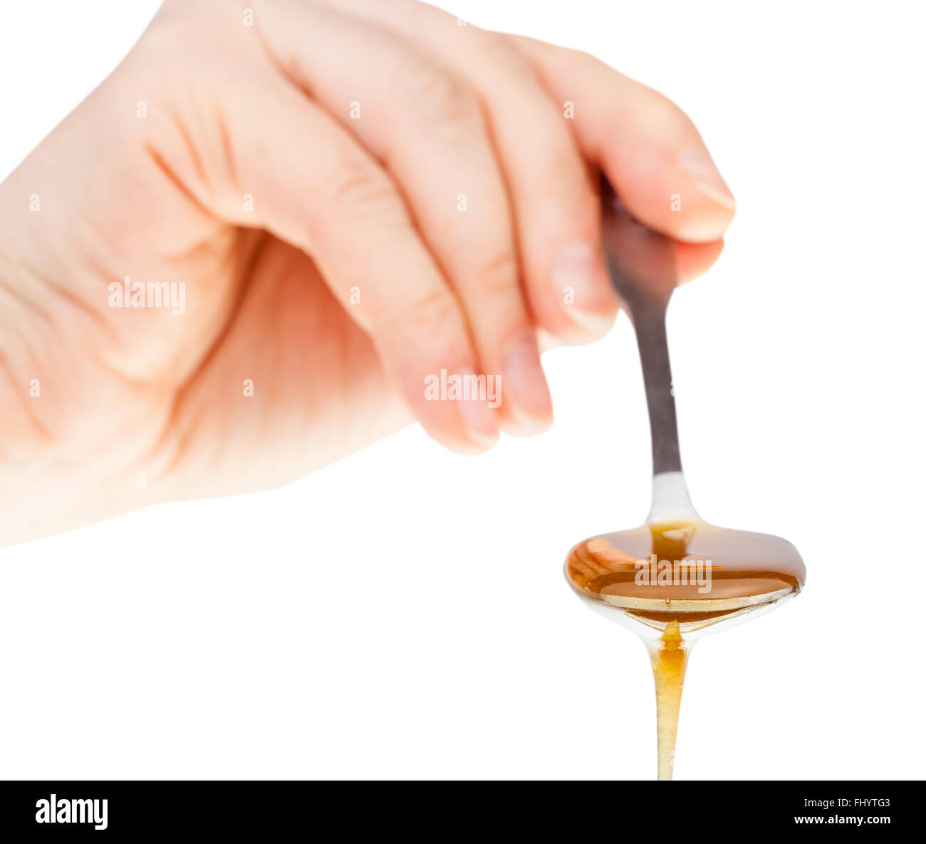 direct view of hand holds metal spoon with clear honey close up isolated on white background Stock Photo
