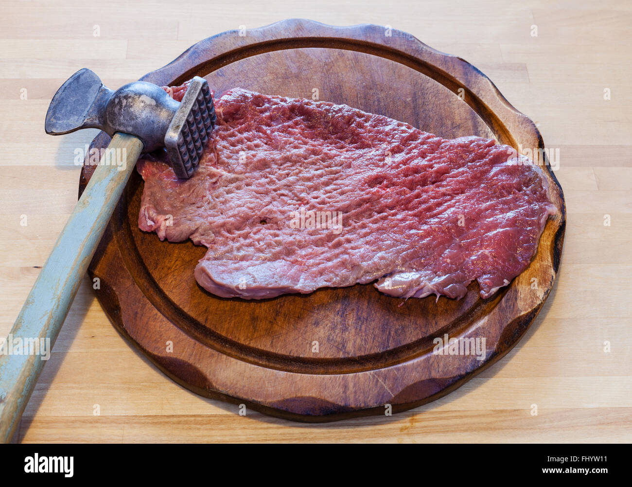 meat tenderizer and beaten slice of veal on cutting board Stock Photo