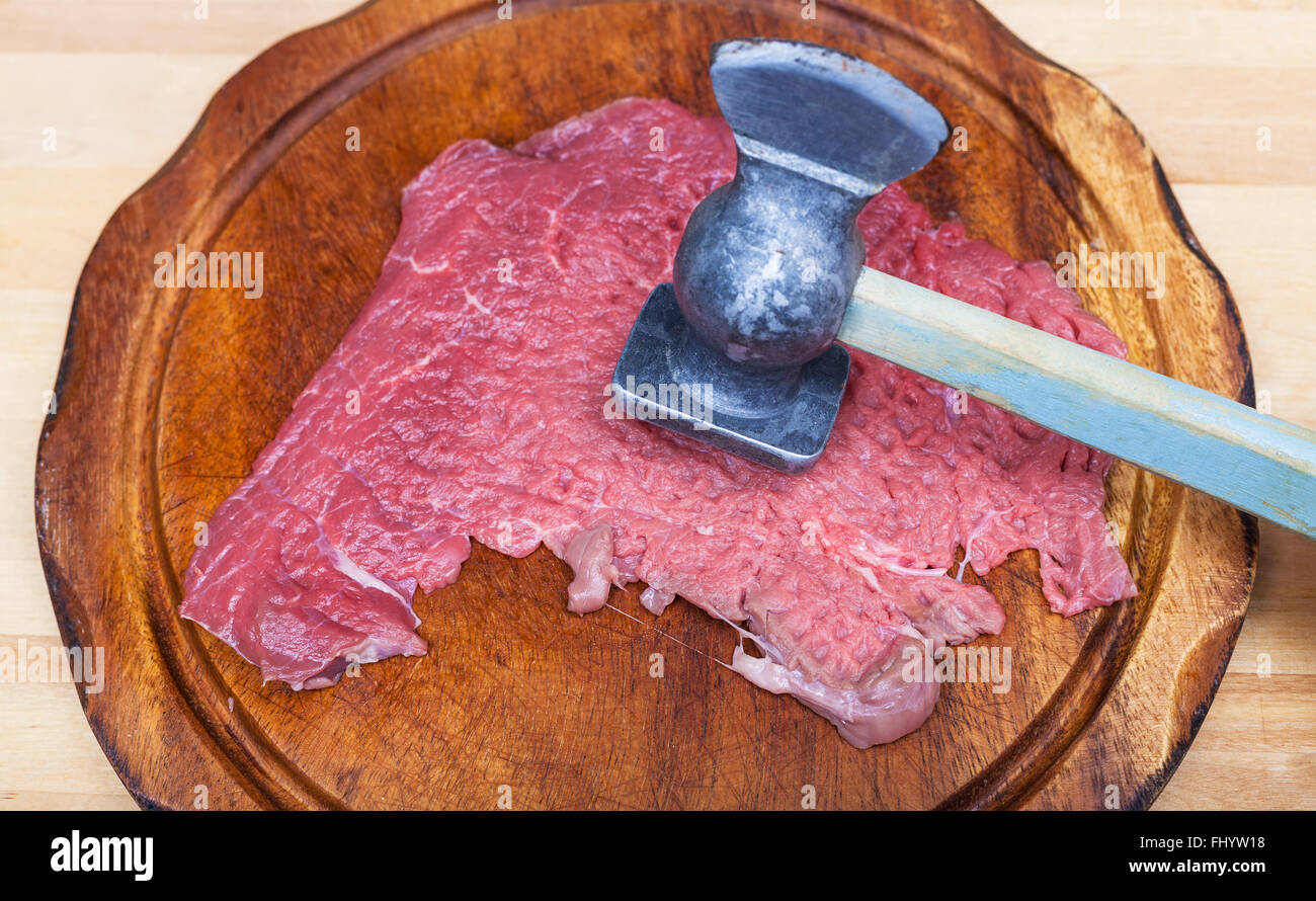 slice of veal is beating by meat tenderizer on cutting board Stock Photo