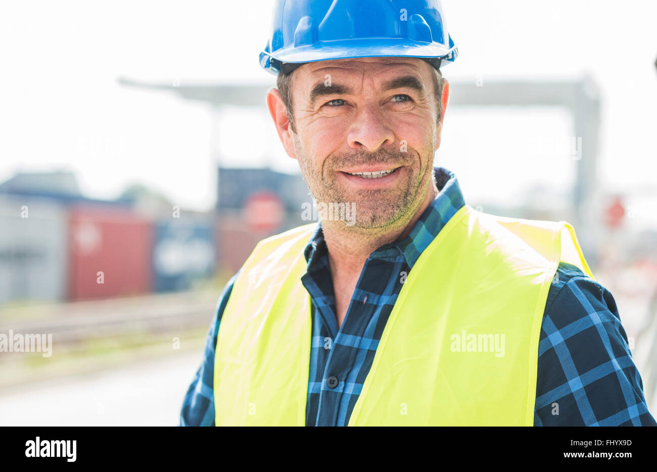 Portrait of confident man wearing hard hat at container port Stock Photo