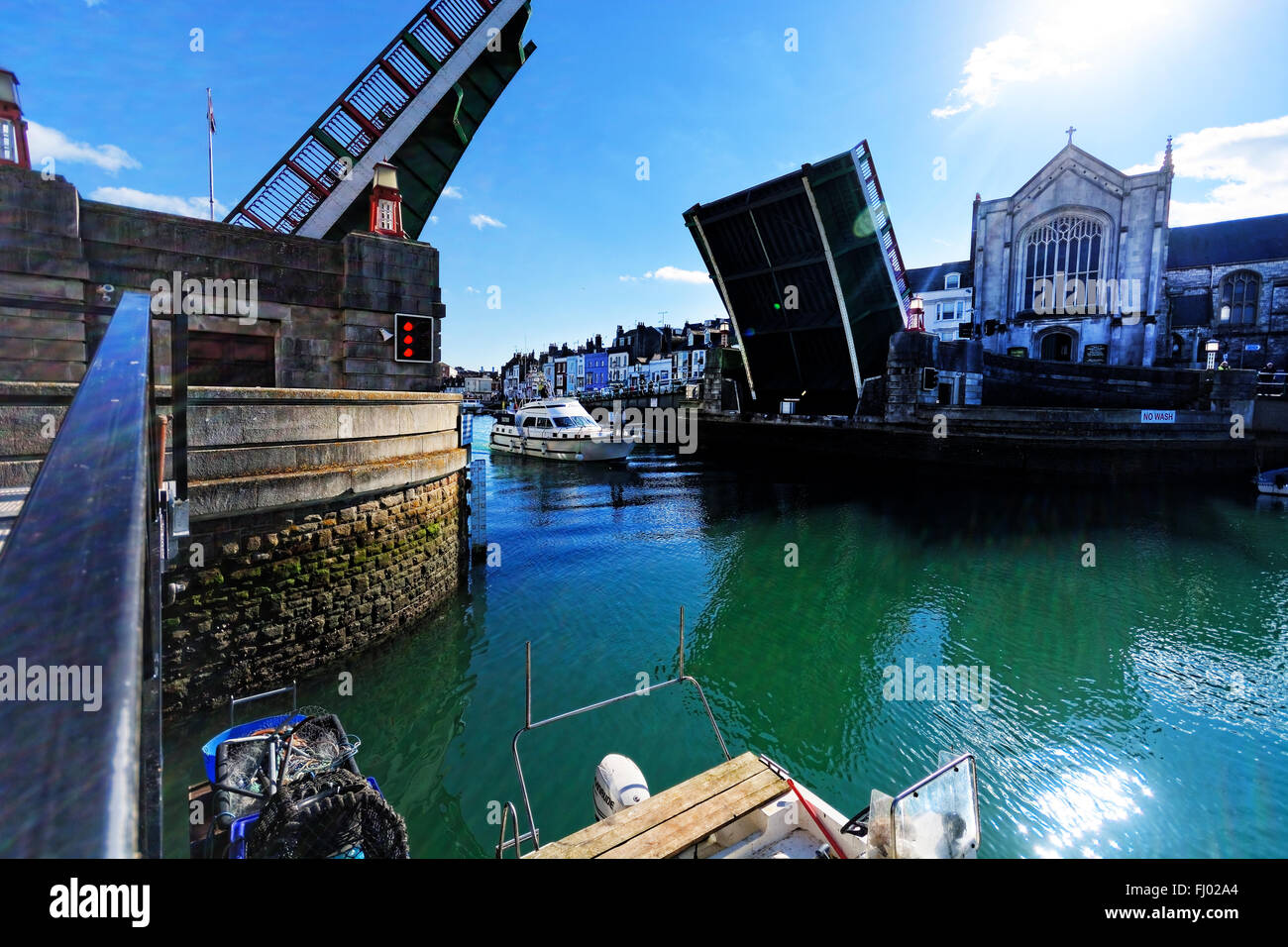 The bascule lifting bridge allows a motor cruiser to pass through en route from the old harbour to the marina at Weymouth, UK Stock Photo