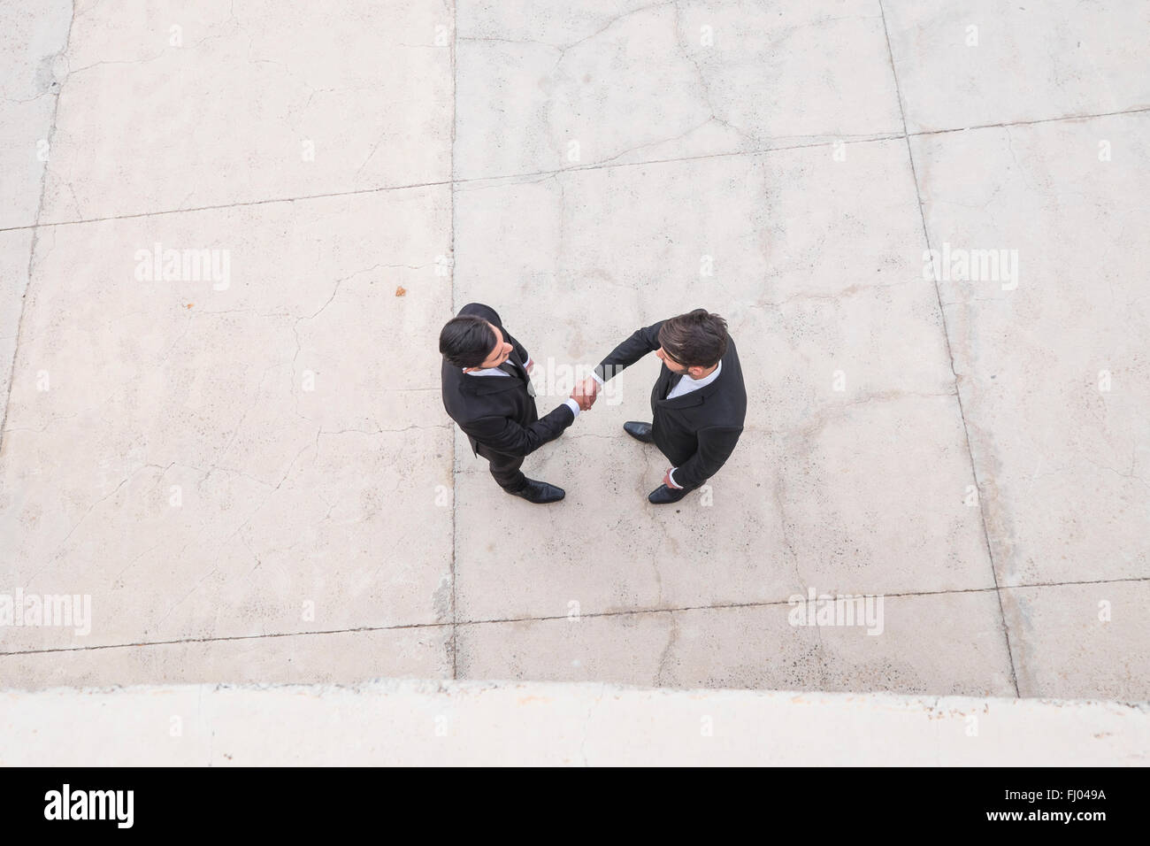 Two businessmen wearing black suits greeting each other Stock Photo - Alamy