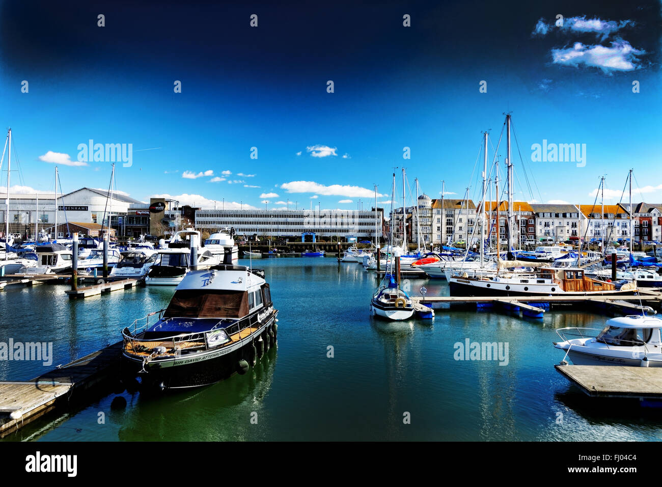 Boats moored at Weymouth marina, UK, in bright sunshine, the town being on the far side; the launch 'Sir David Attenborough' Stock Photo