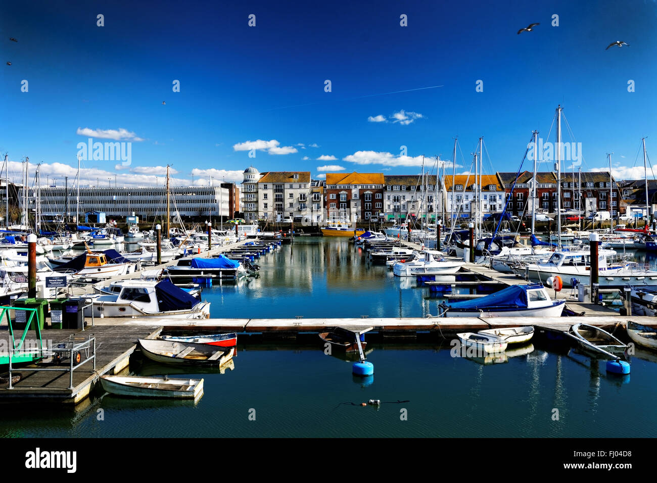 Boats moored at Weymouth marina, UK, in bright sunshine, the town being
