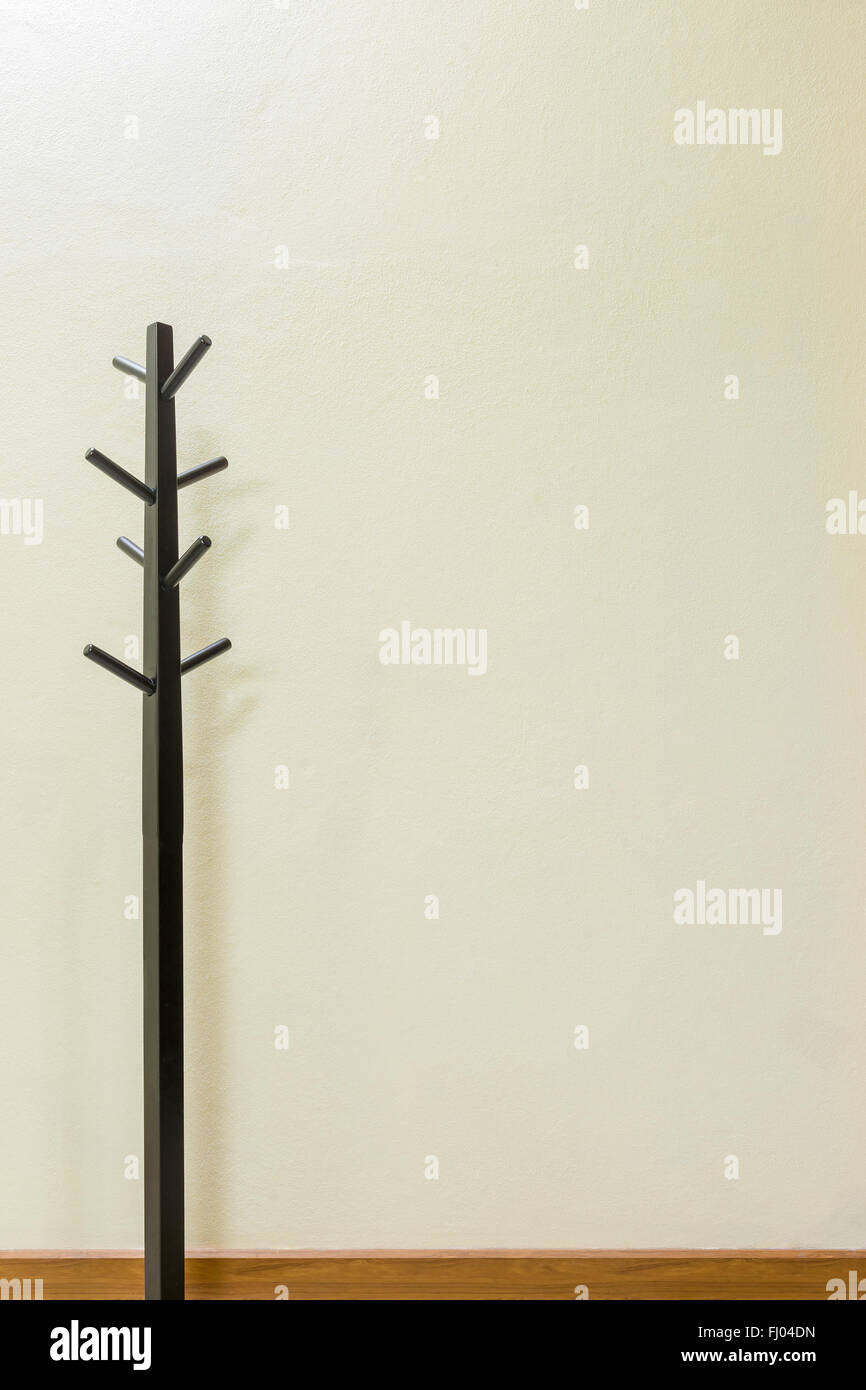 Black wooden coat rack on wall background, space for input text. Stock Photo