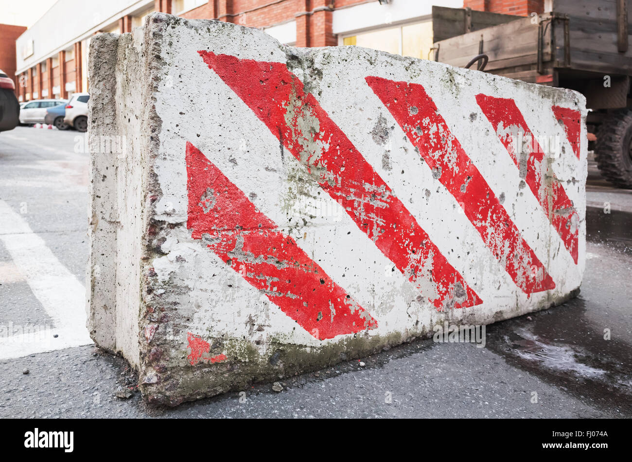 Close-up photo of concrete road block with warning red white diagonal striped pattern Stock Photo