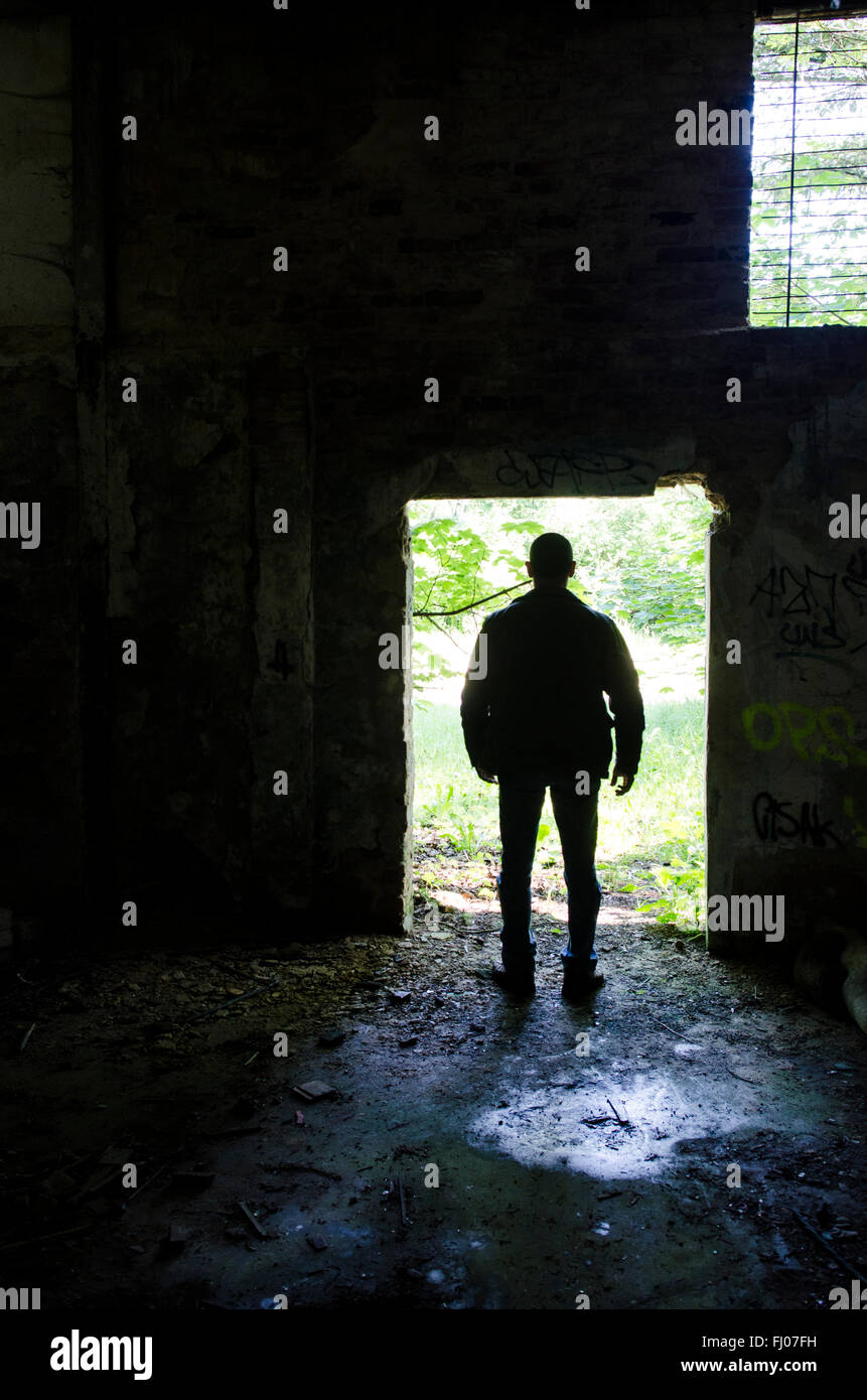 Mysterious male figure standing at the door of a derelict building Stock Photo